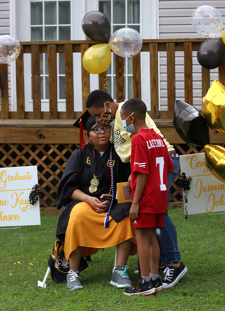 Jasmine-Kay Johnson’s mother Shawntaya Wagner and brother Randy Cannon, 8, embrace her after the graduation parade
